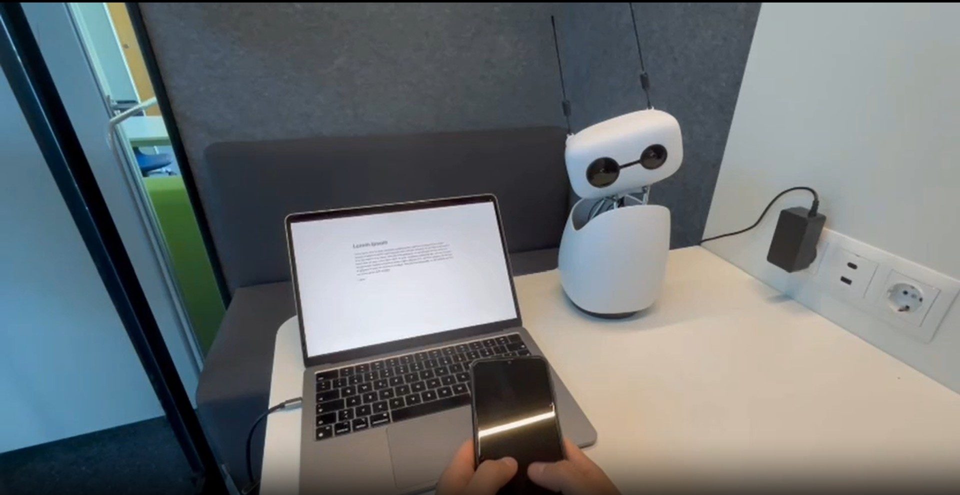 Studien-Setup: Laptop, Reachy Mini und Smartphone aus simulierter Ich-Perspektive
